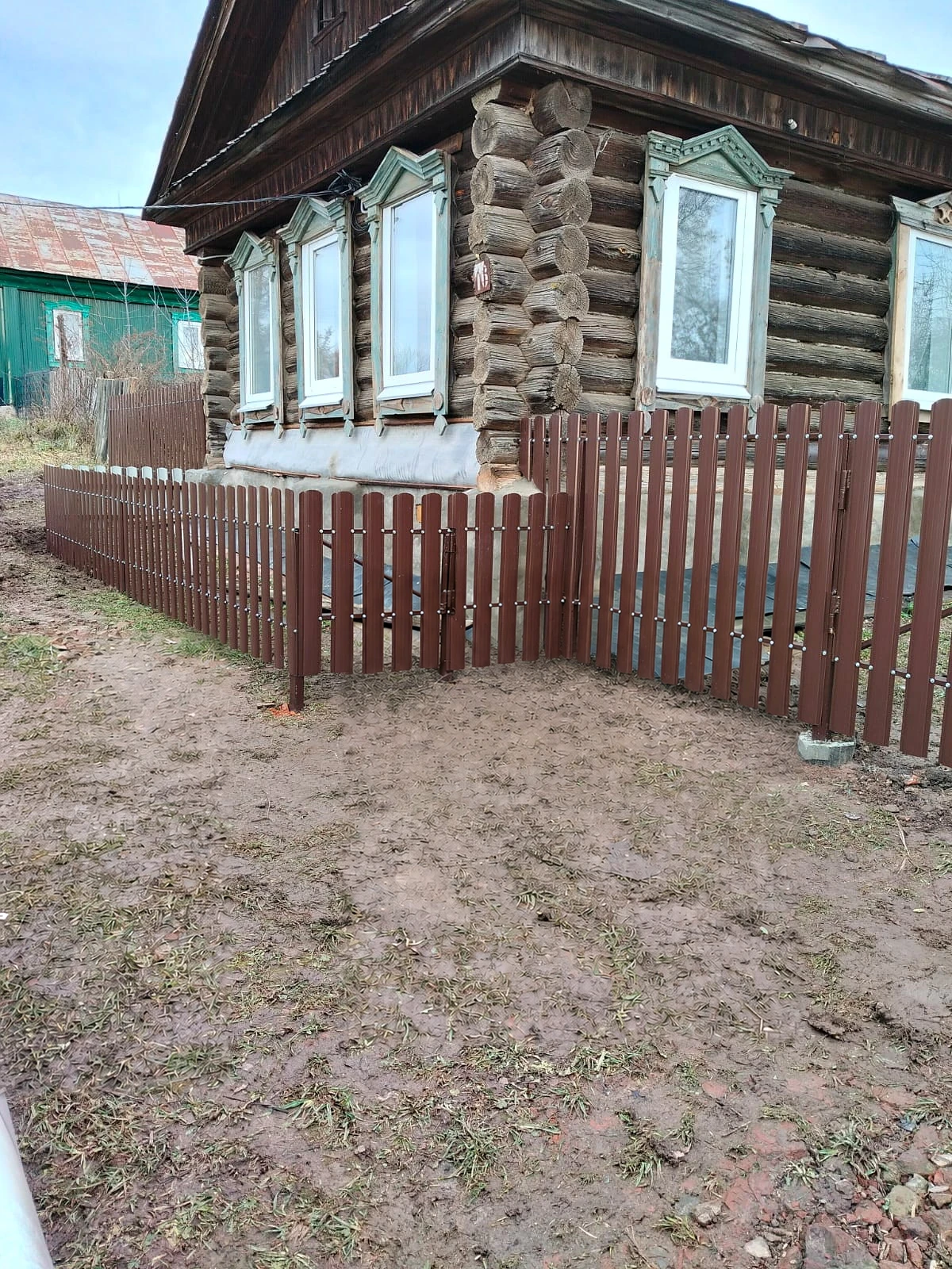 Коричневое металлическое ограждение у деревянного дома