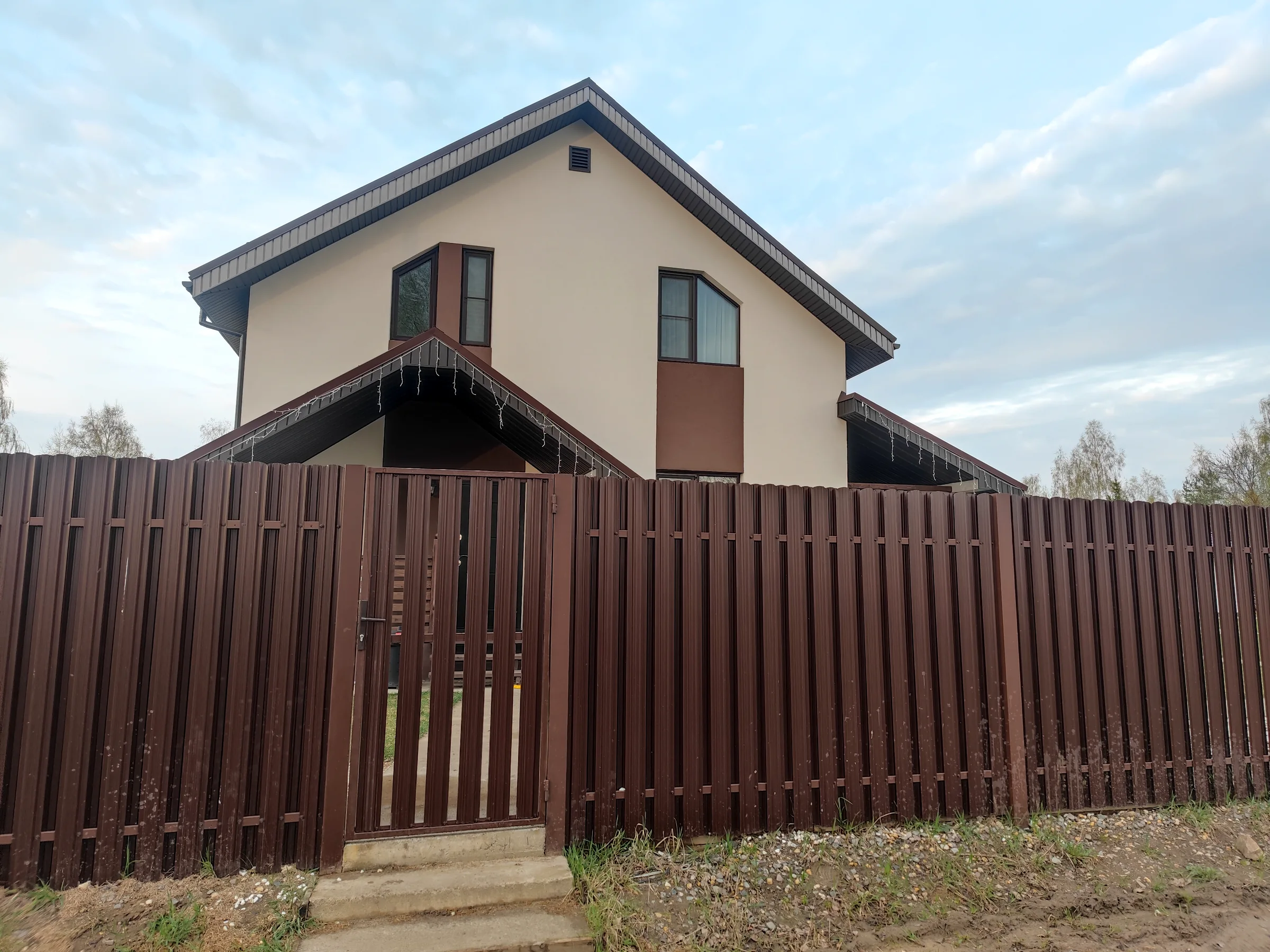 Коричневое ограждение с калиткой у загородного дома